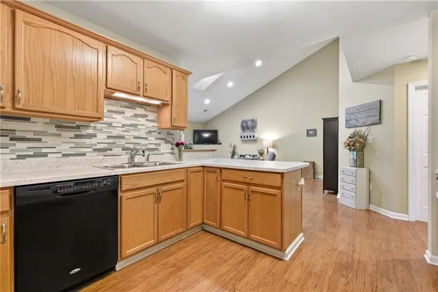 a kitchen with stainless steel appliances granite countertop wooden cabinets a sink and dishwasher with wooden floor