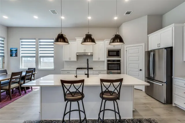 a kitchen with stainless steel appliances kitchen island granite countertop a table chairs stove and refrigerator