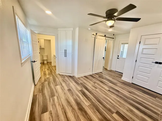 a view of a bedroom with wooden floor and ceiling fan