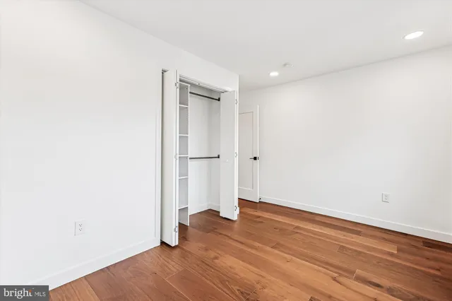 an empty room with wooden floor and entrance