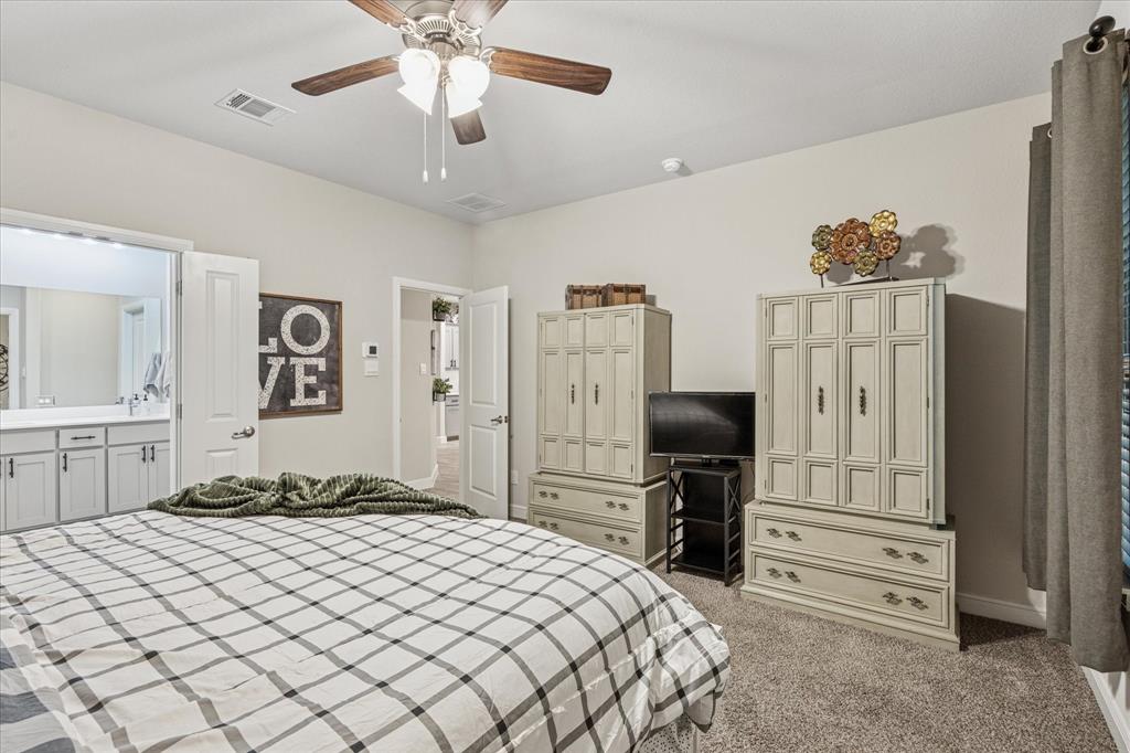 155 Texasage Street Rhome, TX 76078 - Photo 18 of 31 Primary bedroom featuring light carpet, a ceiling fan, connected bathroom, and baseboards