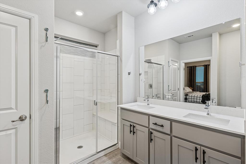 155 Texasage Street Rhome, TX 76078 - Photo 19 of 31 Primary bathroom with a shower stall, ensuite bath, double vanity, and wood finished floors