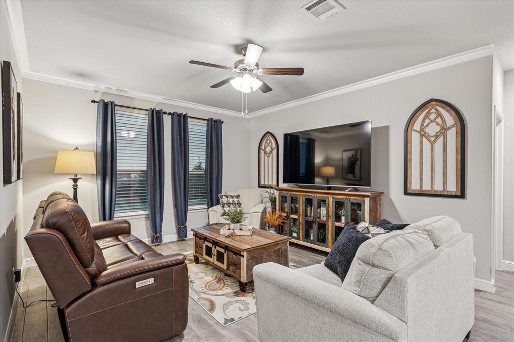 155 Texasage Street Rhome, TX 76078 - Photo 9 of 31 Living area featuring ceiling fan, light wood finished floors, and crown molding