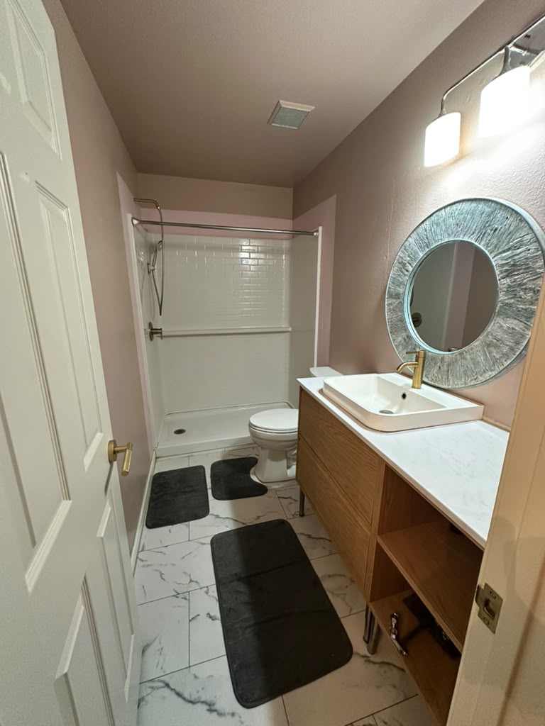 1981 Prairie Rock Way Round Rock, TX 78664 - Photo 12 of 22 Polished tile flooring and a modern wood vanity anchor this renovated bathroom.