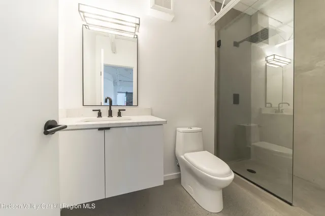 a bathroom with a toilet a sink a mirror and shower