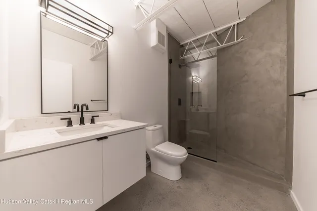 a bathroom with a shower sink vanity mirror and toilet