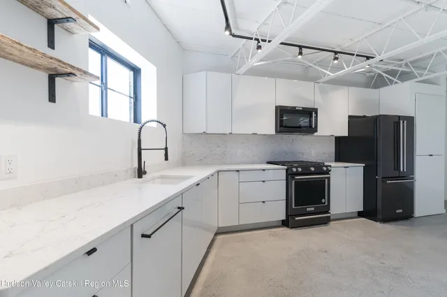 a kitchen with stainless steel appliances granite countertop a sink stove a refrigerator and a microwave