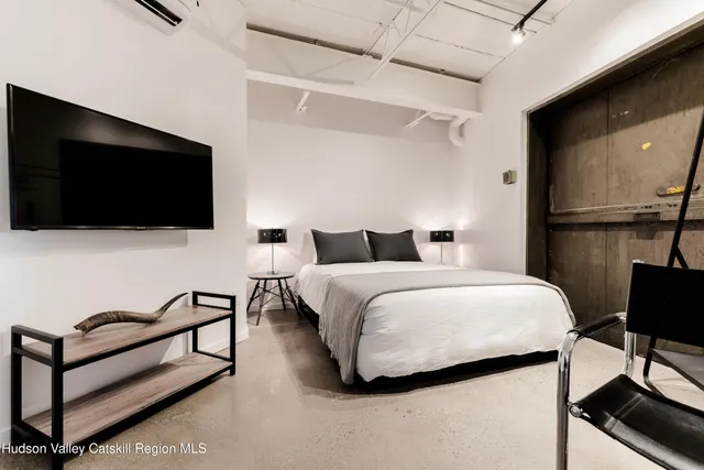 a bedroom with a bed tv and a chair