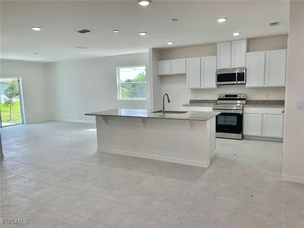 a kitchen with stainless steel appliances granite countertop a stove top oven a sink a refrigerator and white cabinets