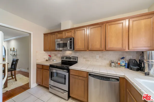 a kitchen with stainless steel appliances granite countertop white cabinets a stove top oven a sink and dishwasher