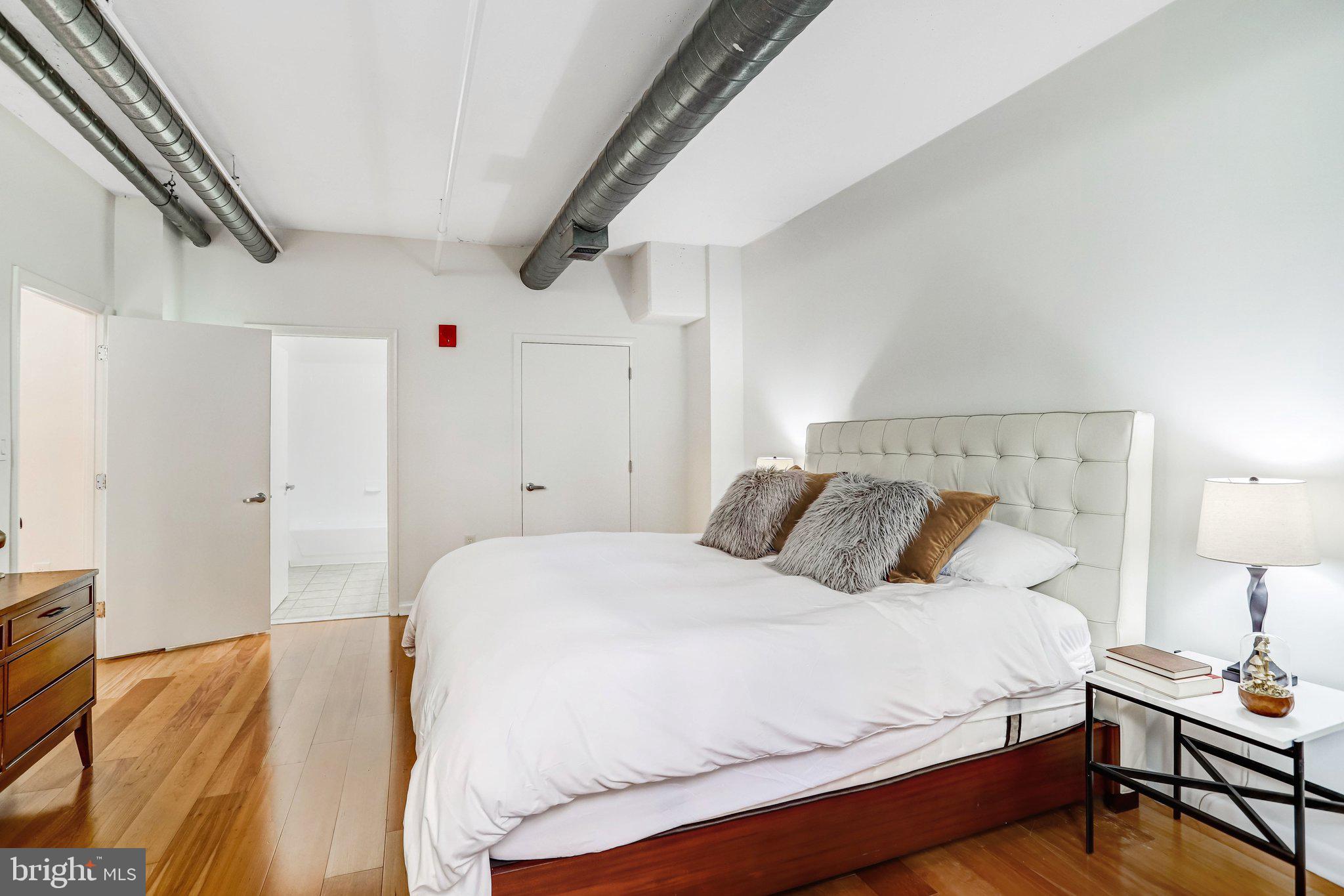 1300 N Street Northwest, Unit 15 Washington, DC 20005 - Photo 11 of 51 a bedroom with a bed and a lamp on the dresser