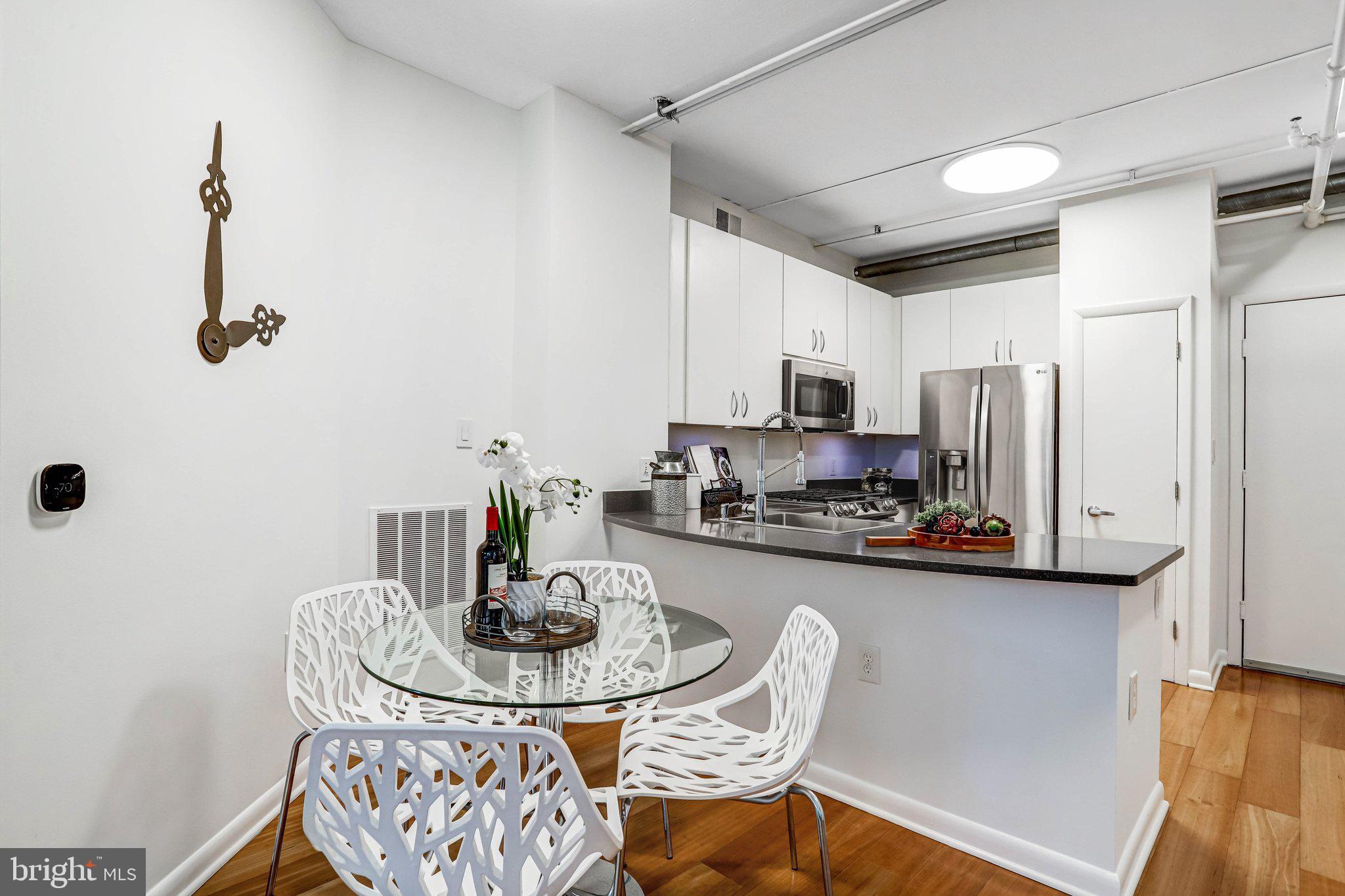 1300 N Street Northwest, Unit 15 Washington, DC 20005 - Photo 28 of 51 a kitchen with stainless steel appliances a dining table and chairs