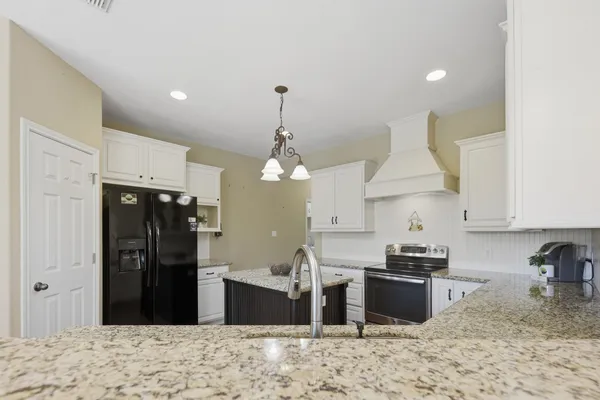 a view of a kitchen with a stove a kitchen island wooden floor ceiling fan and a kitchen view