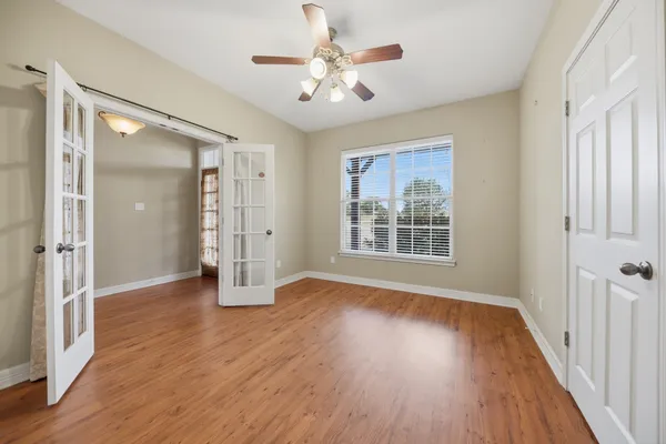 a view of a livingroom with wooden floor a ceiling fan and windows