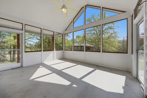 an empty room with windows and ceiling fan