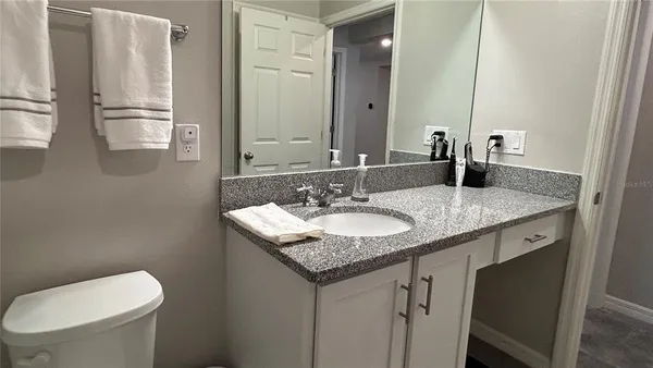 a bathroom with a granite countertop sink a toilet and mirror