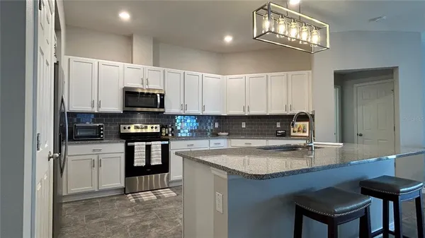 a kitchen with kitchen island granite countertop a sink cabinets stainless steel appliances and a counter top space