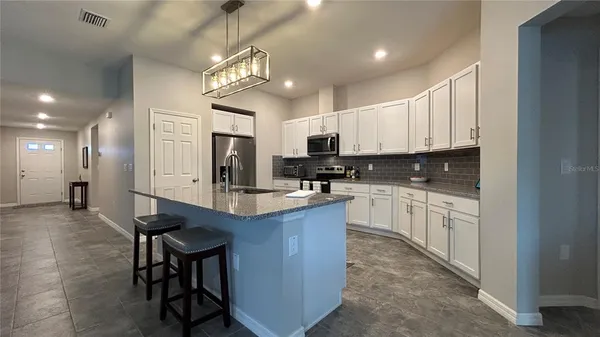 a kitchen with kitchen island granite countertop a sink cabinets and stainless steel appliances
