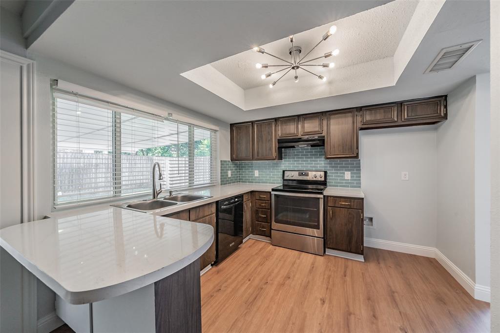 1301 Cedar Ridge Terrace Euless, TX 76039 - Photo 11 of 31 Kitchen features stainless steel electric stove, glass subway tile backsplash and updated lighting.