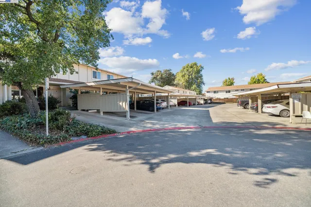a view of a white house next to a yard with big trees