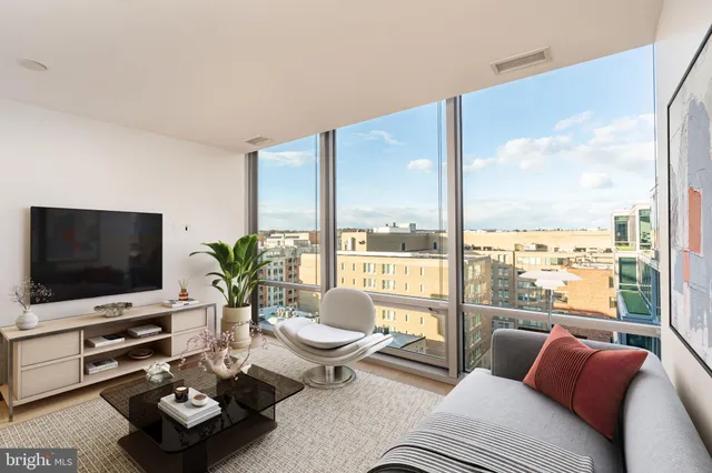 a living room with furniture a flat screen tv and a floor to ceiling window