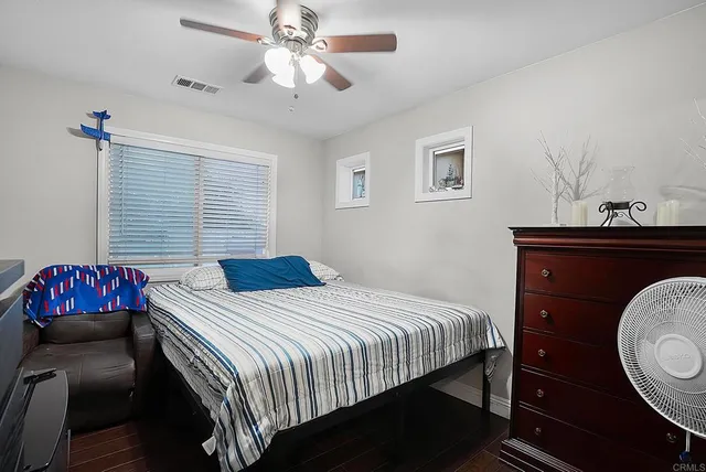 a bedroom with a bed a desk and chair with window