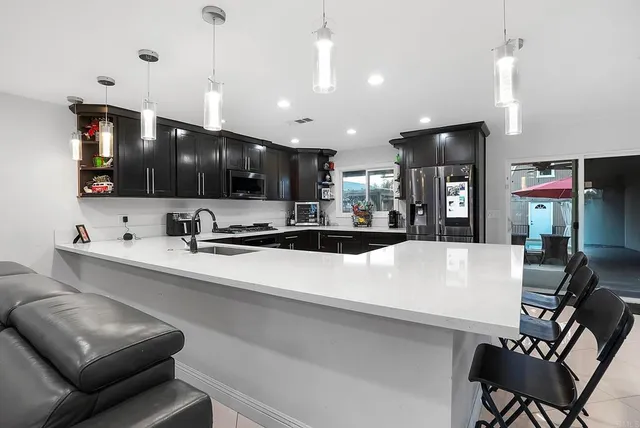 a large kitchen with stainless steel appliances a large counter top a stove and a refrigerator with wooden floor