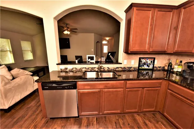 a kitchen with stainless steel appliances granite countertop a sink a stove and a wooden floors