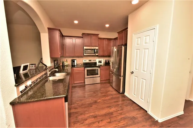 a kitchen with stainless steel appliances granite countertop a refrigerator a stove top oven a sink and dishwasher