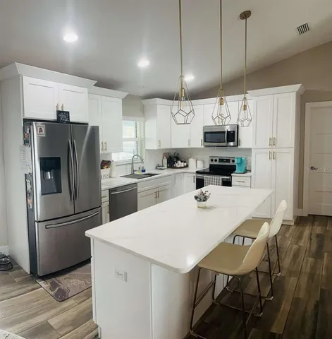 a kitchen with kitchen island a refrigerator a sink a stove and chairs