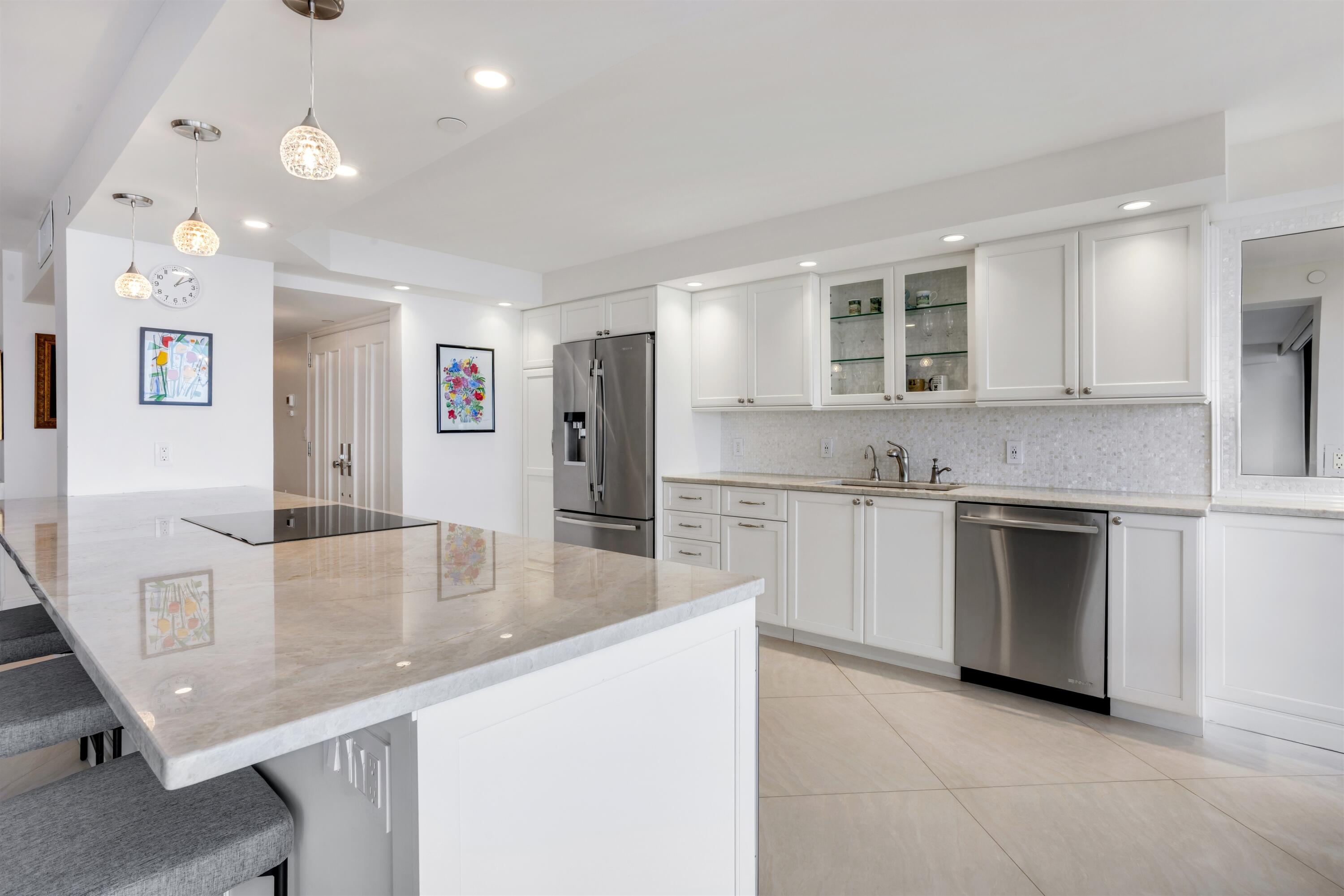 1800 South Ocean Boulevard, Unit 6B Boca Raton, FL 33432 - Photo 11 of 34 a large kitchen with kitchen island a stove a sink a refrigerator and white cabinets with wooden floor