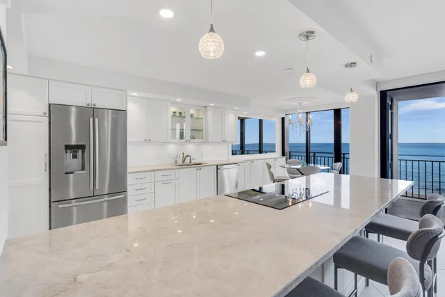 a large kitchen with stainless steel appliances a refrigerator a sink dishwasher a dining table and chairs with wooden floor