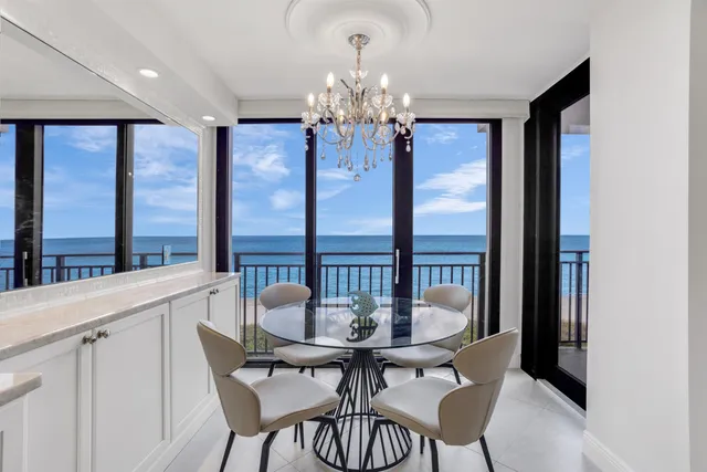 a view of a dining room with furniture a chandelier and large window
