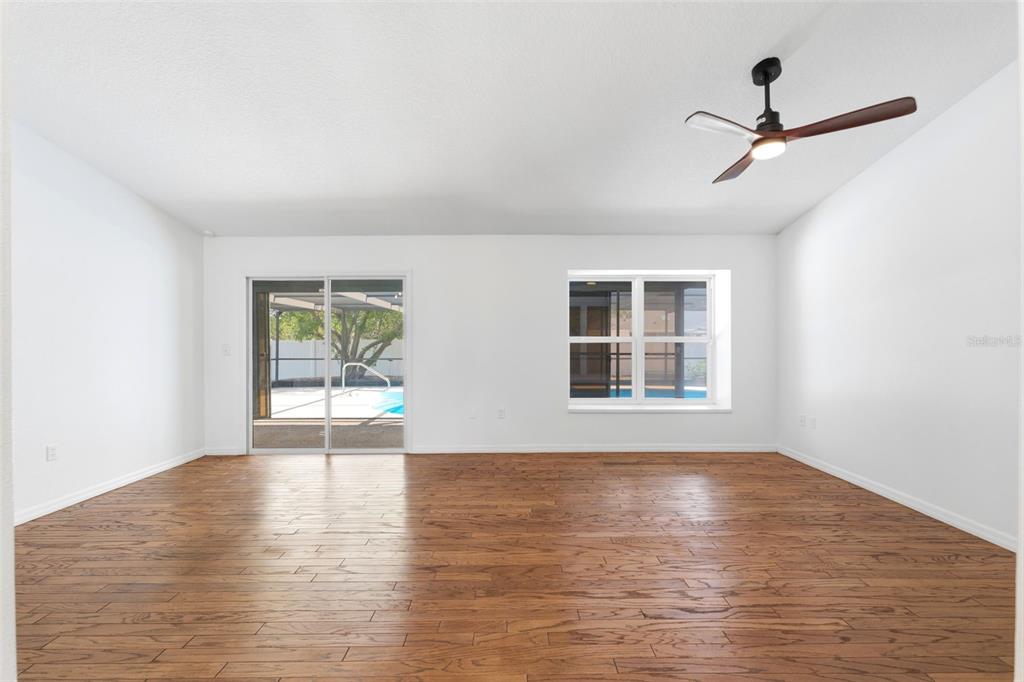 11224 Holbrook Street Spring Hill, FL 34609 - Photo 7 of 55 a view of an empty room with wooden floor and a window