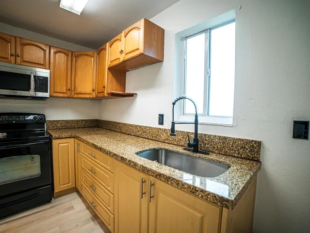 a kitchen with granite countertop cabinets stainless steel appliances and a sink