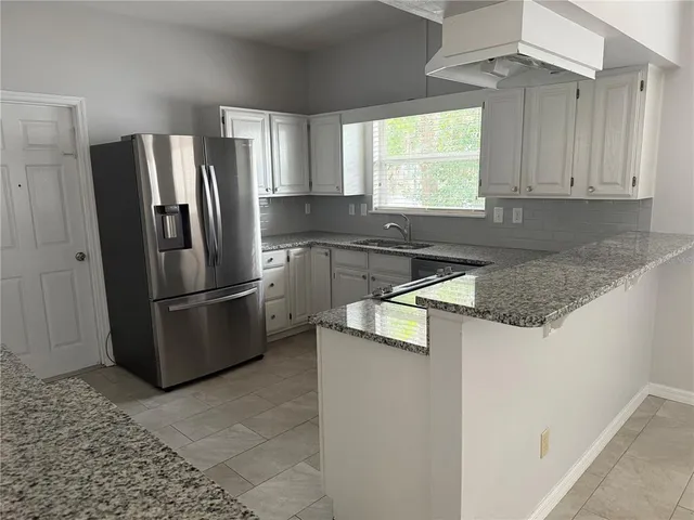 a kitchen with stainless steel appliances granite countertop a refrigerator a sink a stove and island