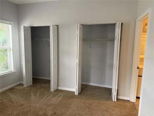 a view of an empty room with windows and closet