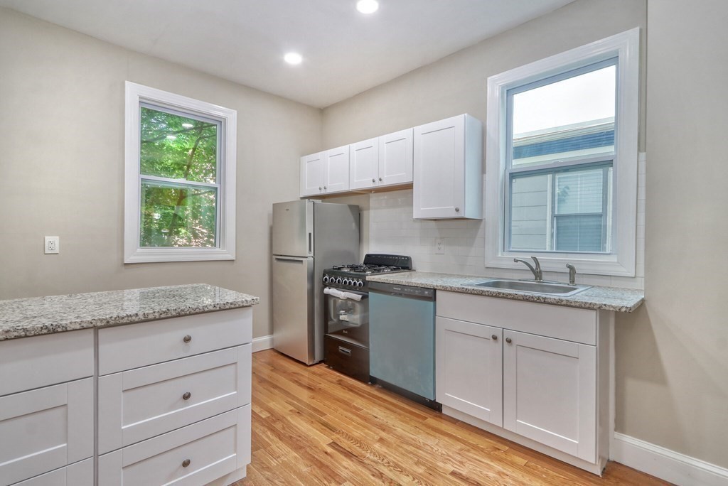 15-17 Pond Street Boston, MA 02130 - Photo 3 of 21 a kitchen with granite countertop cabinets stainless steel appliances a sink and a window