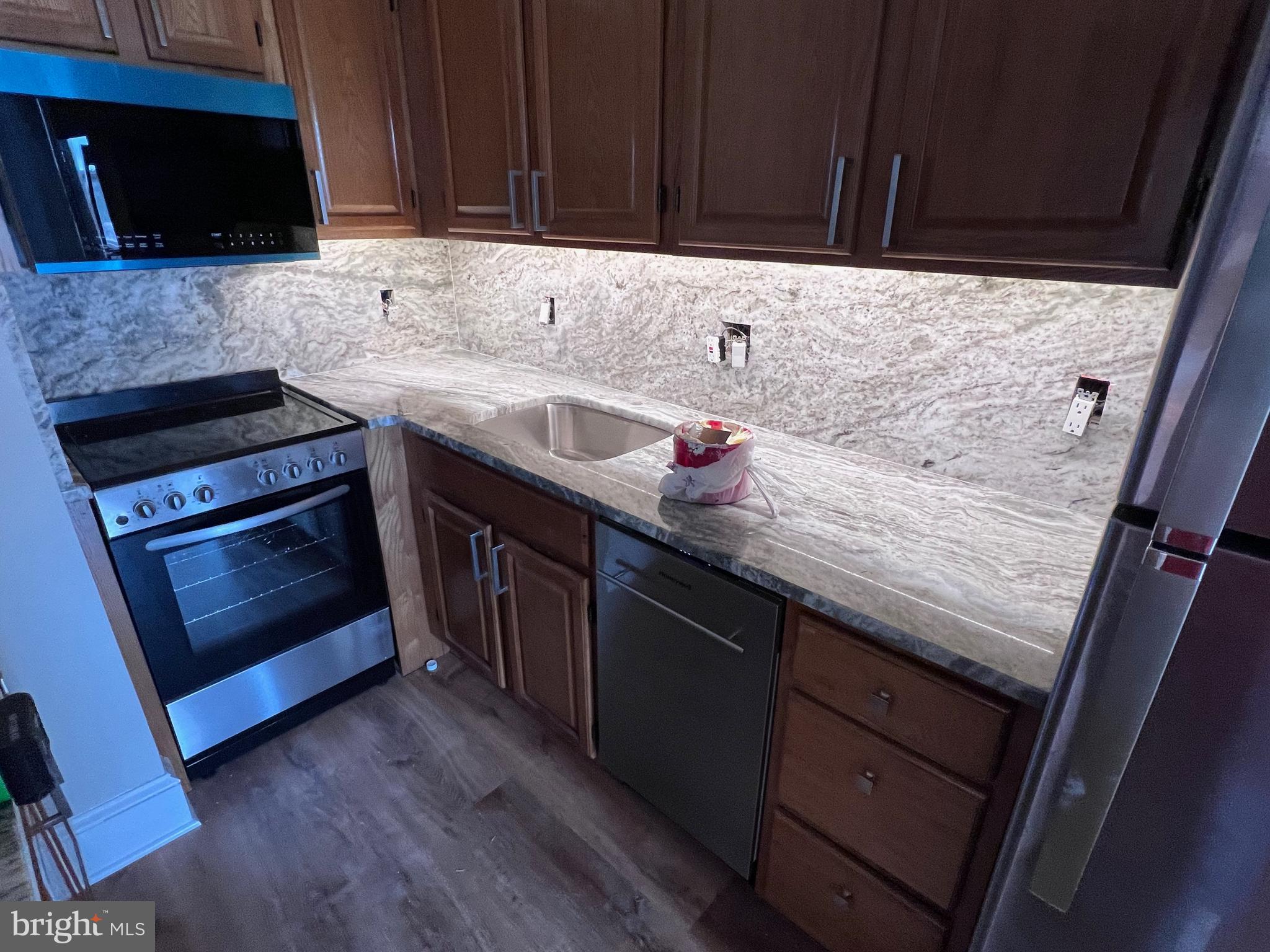 1306 West 13th Street, Unit 1 Wilmington, DE 19806 - Photo 3 of 21 a kitchen with granite countertop a sink dishwasher a stove and a microwave oven on granite countertops