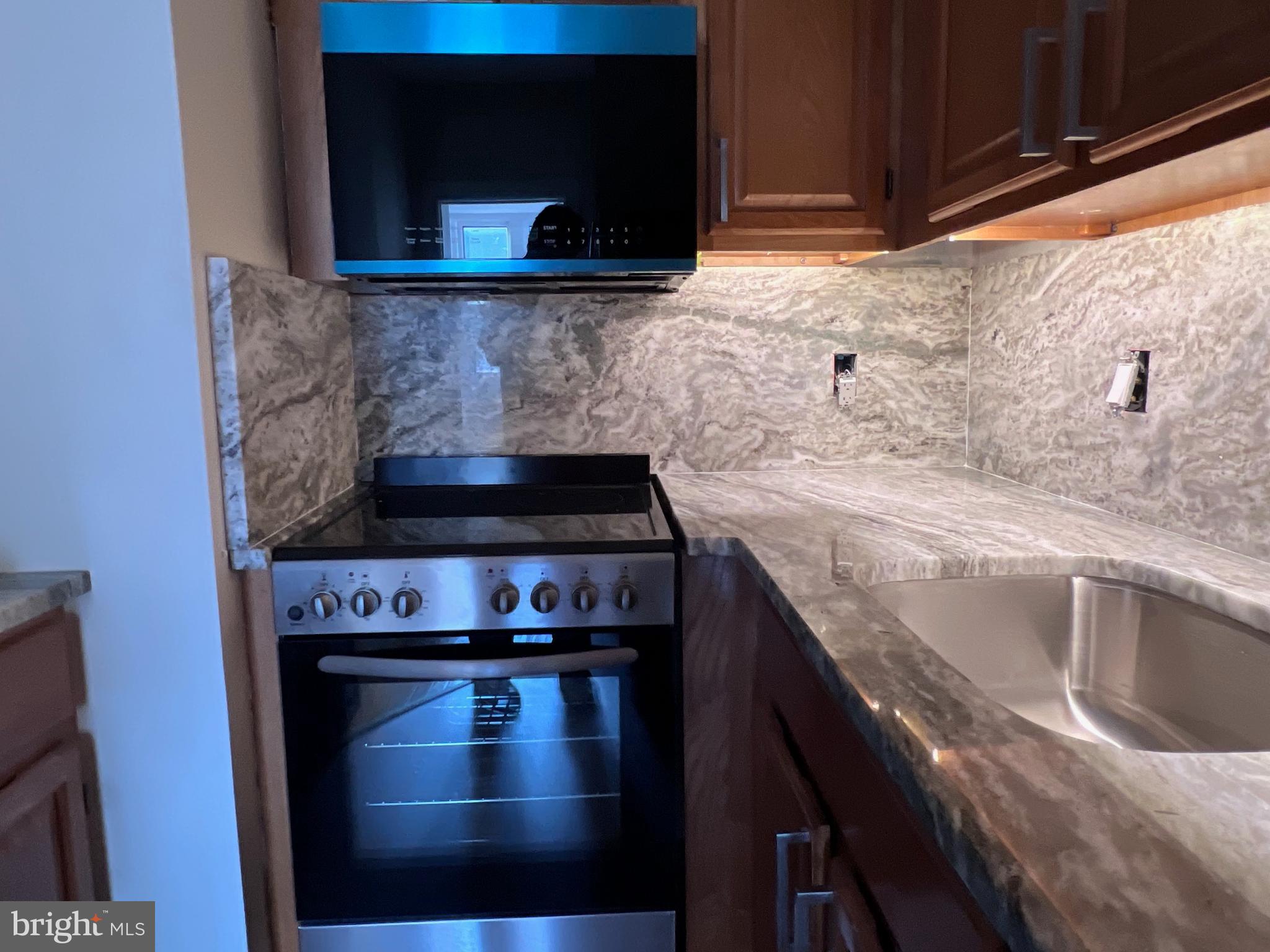1306 West 13th Street, Unit 1 Wilmington, DE 19806 - Photo 4 of 21 a kitchen with granite countertop a stove and a microwave