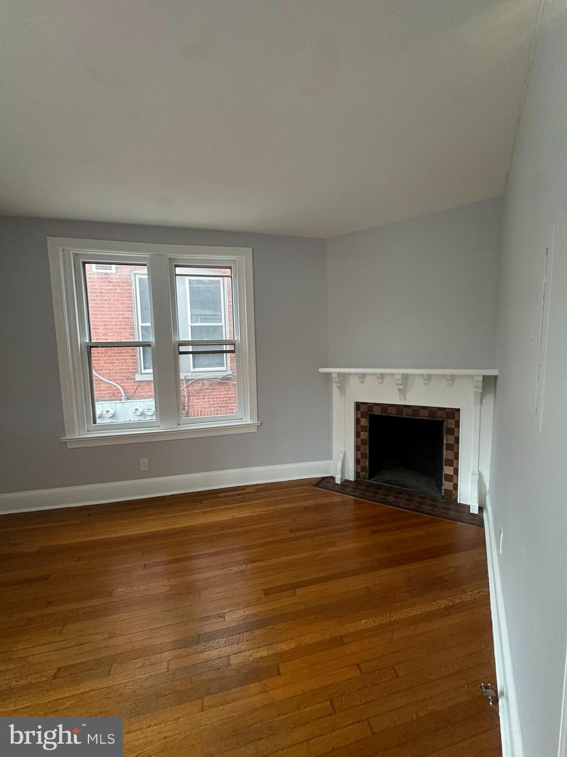 1306 West 13th Street, Unit 1 Wilmington, DE 19806 - Photo 7 of 21 a view of an empty room with wooden floor fireplace and a window