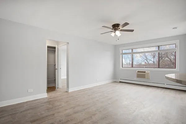 an empty room with chandelier fan and windows