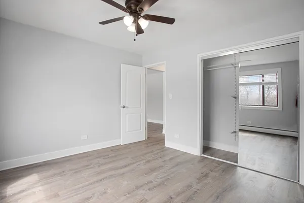 an empty room with wooden floor closet and windows