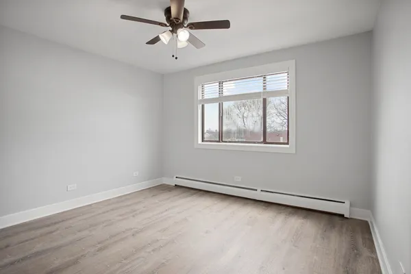 an empty room with a window and ceiling fan