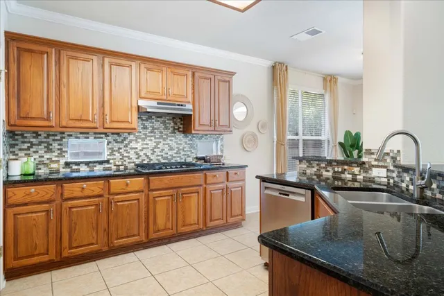 a kitchen with stainless steel appliances granite countertop a sink a stove and a wooden cabinets