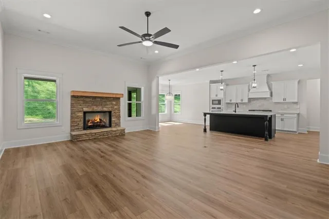 a view of kitchen and empty room with wooden floor fireplace