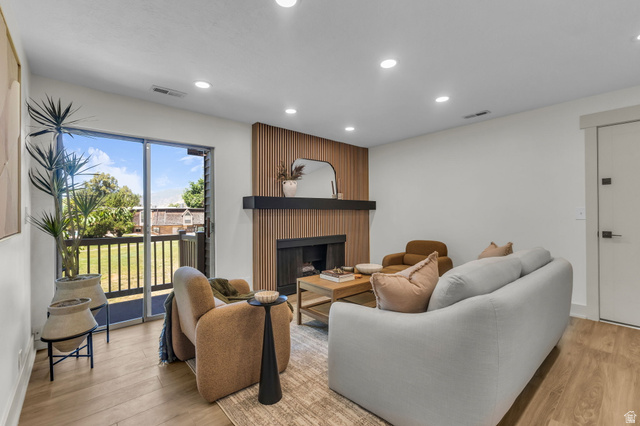 88 West 50 South, Unit C8 Centerville, UT 84014 - Photo 2 of 29 Living area featuring a fireplace with a wood-slat accent wall, a black mantel, recessed ceiling lighting, and wood-finish flooring