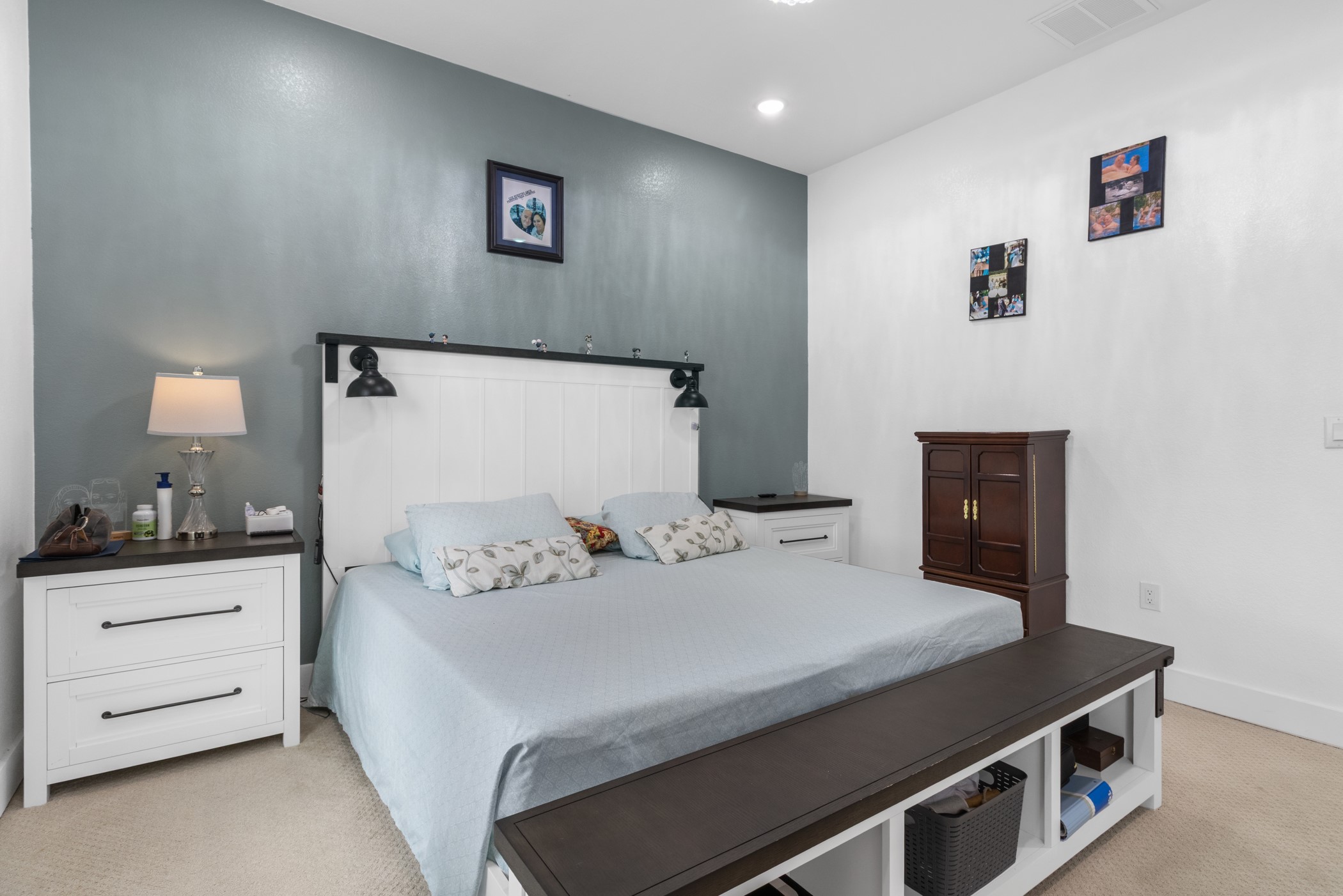 123 Zacate Street Elgin, TX 78621 - Photo 11 of 33 Bedroom featuring a white paneled headboard with integrated sconce lighting, an accent wall, white walls, and light-colored carpeting