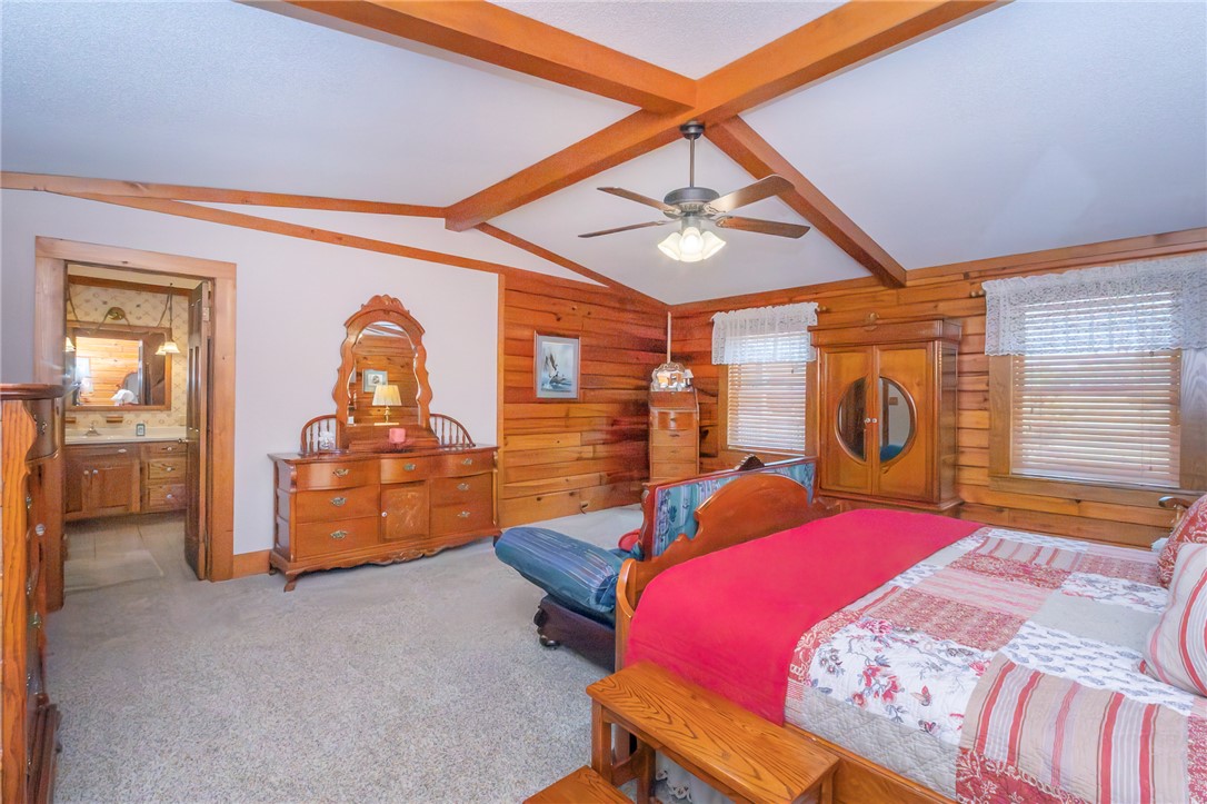 911 State Rd S-4-203 Belton, SC 29627 - Photo 24 of 49 A rustic primary bedroom features high vaulted ceilings and exposed wooden beams.