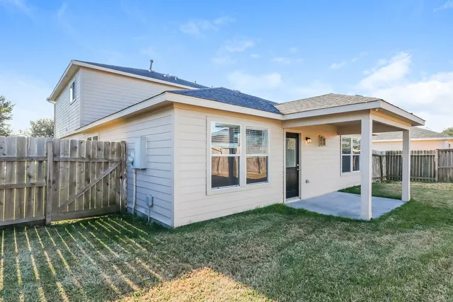 a view of a house with backyard and wooden fence